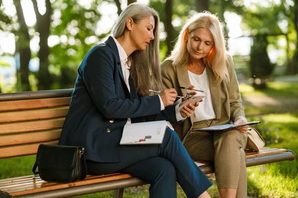 Parkta çalışırken cep telefonu kullanan çok kültürlü iş kadınları.
