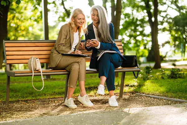 Mature Multiracial Businesswomen Using Cellphone While Working Park Outdoors — Fotografia de Stock