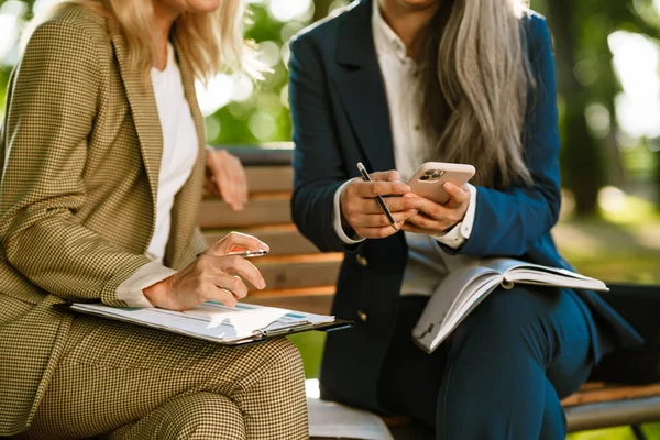 Parkta çalışırken cep telefonu kullanan çok kültürlü iş kadınları.