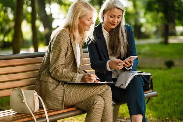 Parkta çalışırken cep telefonu kullanan çok kültürlü iş kadınları.