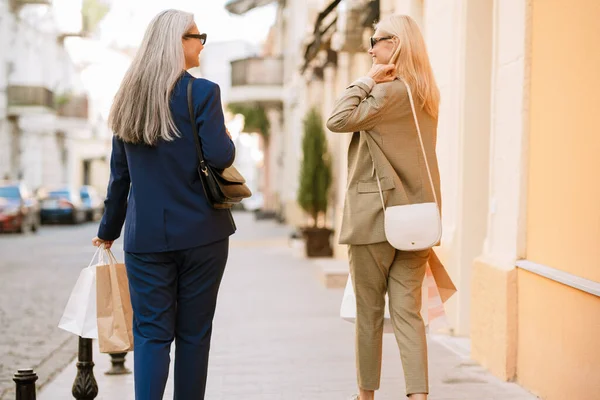 Mature Multiracial Women Talking While Walking Shopping Bags Outdoors —  Fotos de Stock