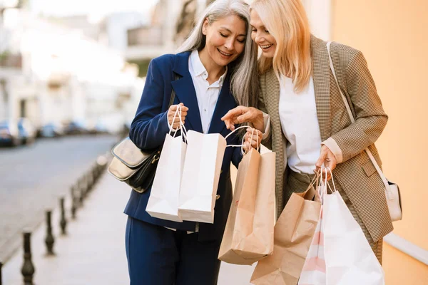 Mature Multiracial Women Talking Looking Shopping Bags While Walking Outdoors — Stock Photo, Image