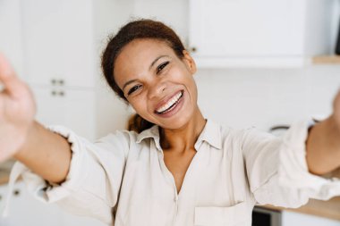Genç siyahi kadın evde selfie çekerken gülüyor.