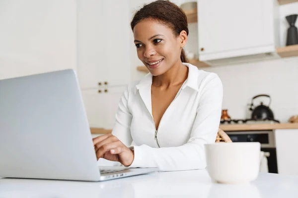 Black Woman Smiling While Working Laptop Kitchen Home — Stockfoto