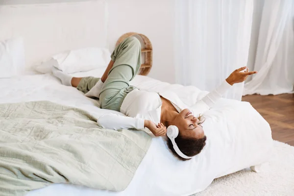 Young Black Woman Listening Music Headphones While Lying Bed Home — Foto de Stock