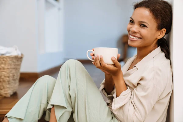 坐在楼梯上的黑人妇女笑着喝茶 — 图库照片