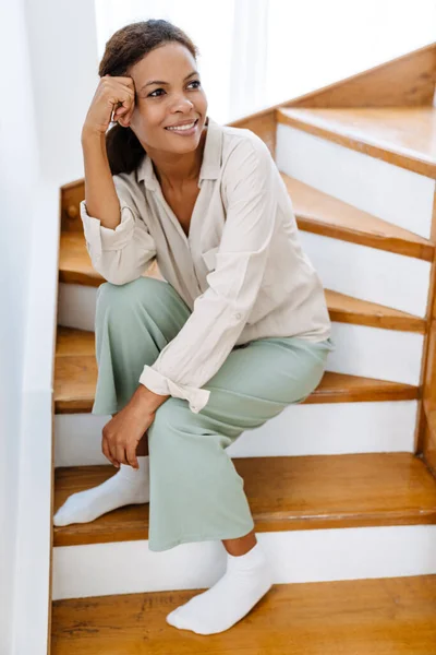 Evdeki Ahşap Merdivenlerde Otururken Gülümseyen Genç Zenci Kadın — Stok fotoğraf