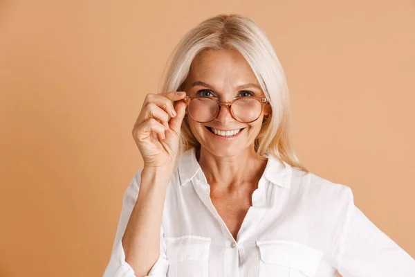 Gözlüklü Olgun Bir Kadın Gülümsüyor Bej Arka Planda Izole Edilmiş — Stok fotoğraf