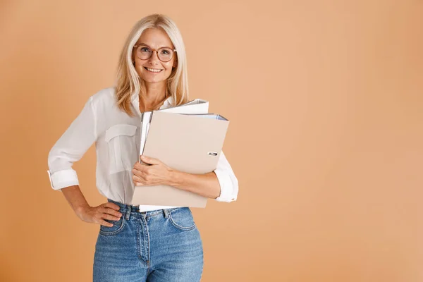 Mature Woman Eyeglasses Smiling Holding Paper Folders Isolated Beige Background — Stockfoto