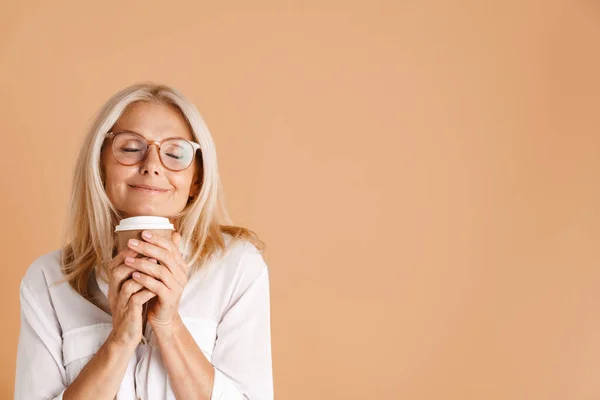 Mature Woman Eyeglasses Smiling While Drinking Coffee Isolated Beige Background — Stock Fotó