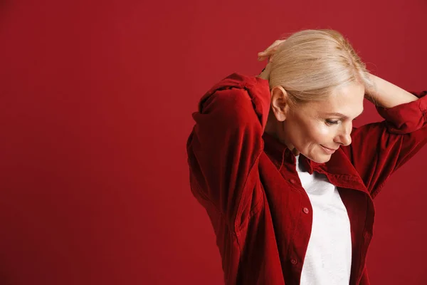 Mature Blonde Woman Wearing Shirt Smiling Doing Hairstyle Isolated Red — Stock fotografie