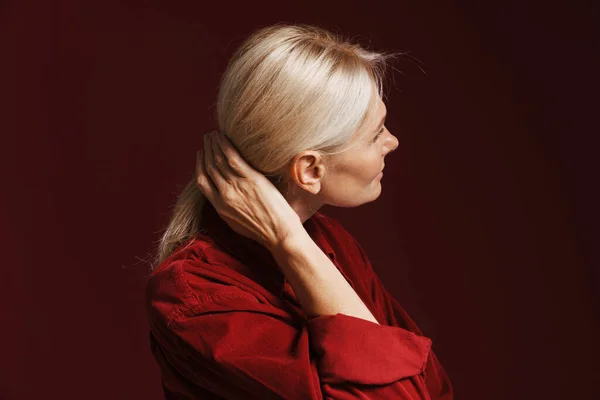 Mature Blonde Woman Wearing Shirt Smiling Doing Hairstyle Isolated Red — 스톡 사진