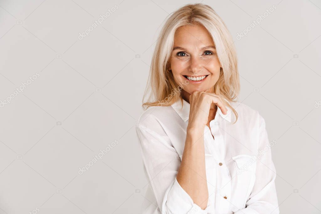 Mature blonde woman wearing shirt smiling and looking at camera isolated over white background