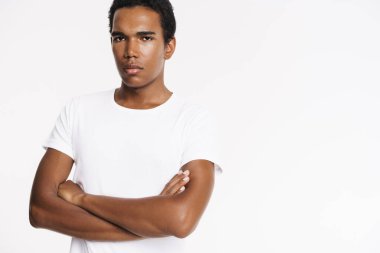 Genç siyah adam tişört giyip beyaz duvarın üzerinden izole edilmiş kameraya bakıyor.