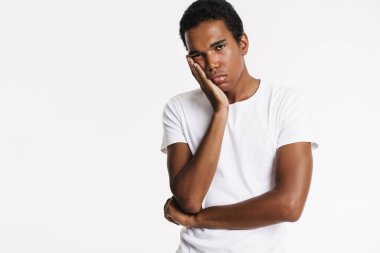 Kafasını kaldırırken kameraya bakan yorgun siyah adam beyaz duvarın üzerinden izole edilmiş.