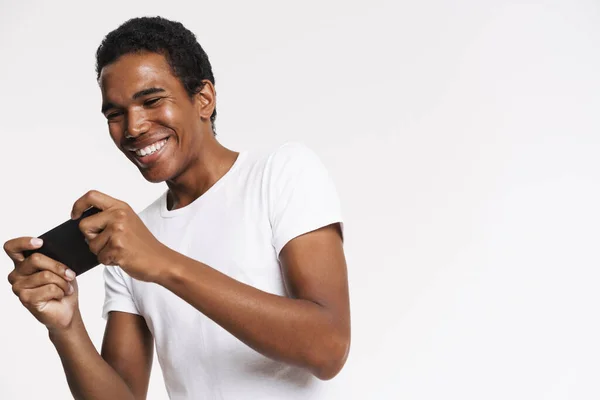 Joven Hombre Negro Sonriendo Mientras Juega Juego Línea Teléfono Celular —  Fotos de Stock