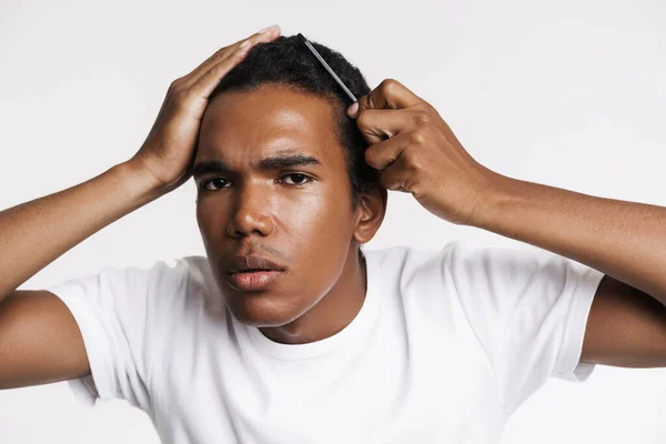 Young Black Man Looking Camera While Combing His Hair Isolated — Stockfoto
