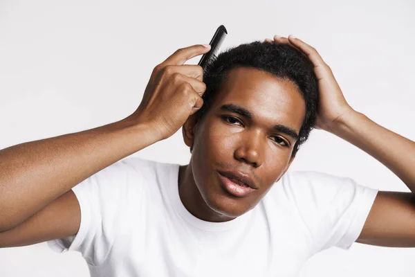 Young Black Man Looking Camera While Combing His Hair Isolated — Stockfoto