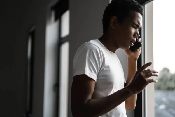 Young Black Man Talking Cellphone While Standing Window Indoors — Stock Fotó