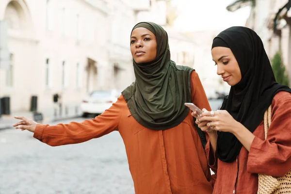 Multiracial Muslim Women Using Mobile Phone Waving Hand Taxi City — Stockfoto