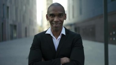 Gülümseyen Afrikalı işadamı sokaktaki kameraya bakıyor.