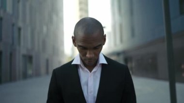 Kendinden emin Afrikalı işadamı sokakta kameraya bakıyor.