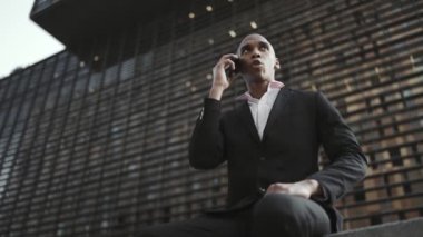 Düşünceli Afrikalı işadamı sokakta konuşuyor.