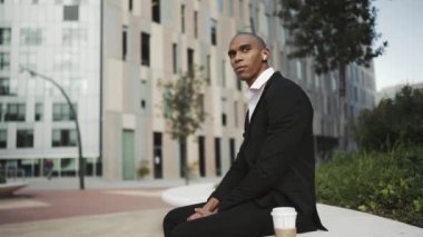 Dışarıda kulaklıkla müzik dinleyen yakışıklı Afrikalı iş adamı.