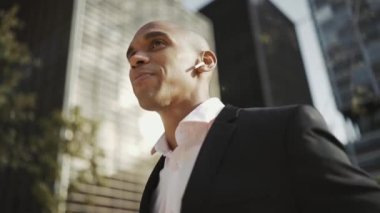 Dışarıda kulaklıkla konuşan neşeli Afrikalı işadamı.