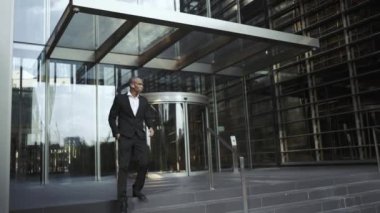 Kulaklıklı ciddi bir Afrikalı işadamı dışarıda yürüyor.