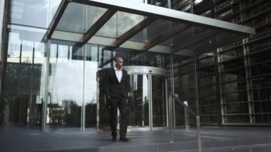 Kulaklıklı konsantre Afrikalı işadamı dışarıda yürüyor.