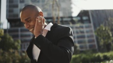 Dışarıda kulaklıkla konuşan gülen Afrikalı işadamı.