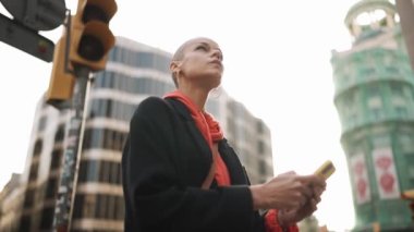 Sokakta telefonla haritaya bakan konsantre kel kadın.