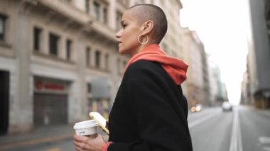 Dalgın kel kadın akıllı telefonla mesaj atıyor ve sokakta yürüyor.