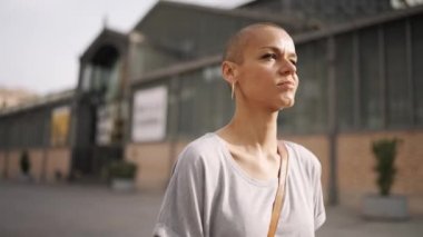 Tişört giyen mutlu kel kadın dışarıda yürüyor.