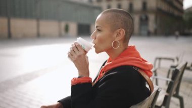 Yakışıklı kel kadın bankta kahve içiyor.