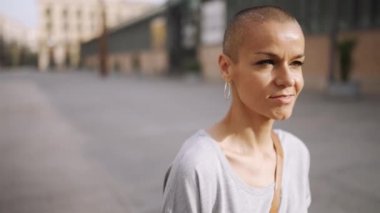 Gülümseyen kel kadın tişört giyip dışarı çıkıyor.