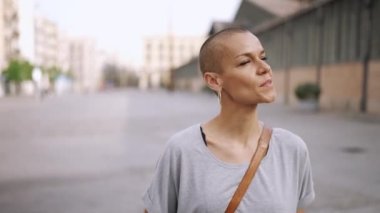 Tişört giyen neşeli kel kadın dışarıda yürüyor.