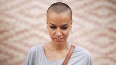 Tişört giyen yakışıklı, kel kadın kameraya dışarıda bakıyor.