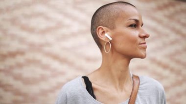 Tişört giyen yakışıklı kel kadın açık havada müzik dinliyor.