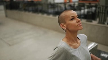 Tişört giyen kendine güvenen kel kadın bankta oturuyor.