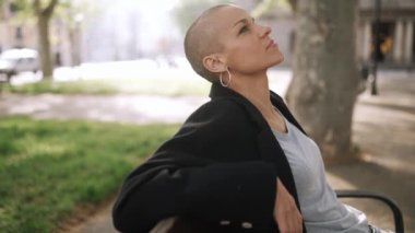 Parktaki bankta oturan yakışıklı kel kadın.