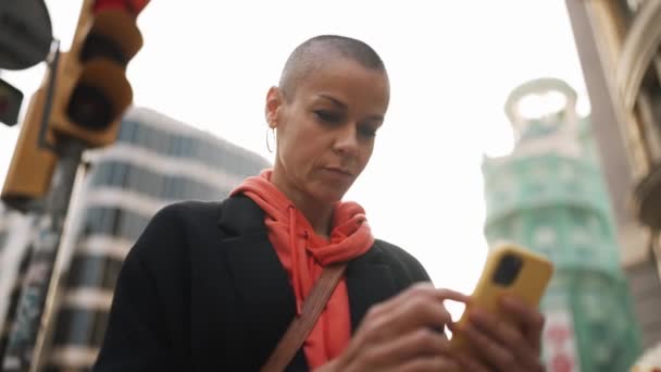 Σκεπτική Φαλακρή Γυναίκα Κοιτάζει Τηλέφωνο Στο Δρόμο — Αρχείο Βίντεο