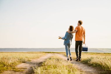 Genç, çok ırklı bir çift, kasaba yolunda daha havalı çanta ve haritayla yürüyor.