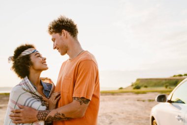 Genç, çok ırklı bir çift yolculuk boyunca arabada durup gülerek ve kucaklaşarak