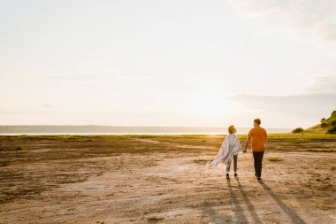 Young multiracial couple holding hands while walking together outdoors