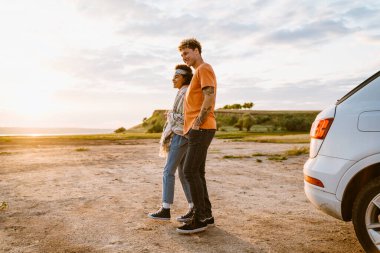 Araba yolculuğu sırasında gülümseyen ve kucaklaşan çok kültürlü genç bir çift.