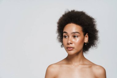 Black curly shirtless woman posing and looking aside isolated over white background