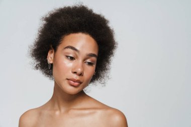 Black curly shirtless woman posing and looking downward isolated over white background