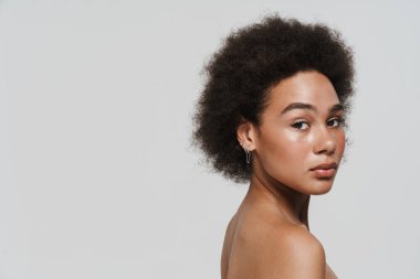 Black curly shirtless woman posing and looking at camera isolated over white background
